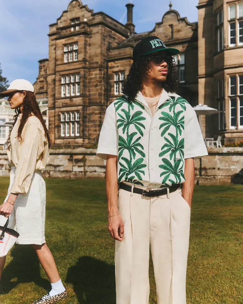 Model in a summer menswear editorial wearing a Jacquemus vacation shirt, Dickies trousers, Bass Weejuns loafers and a Patta cap.