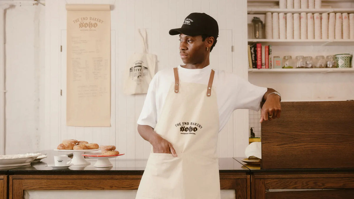 Man in bakery wearing an apron and Percival hat