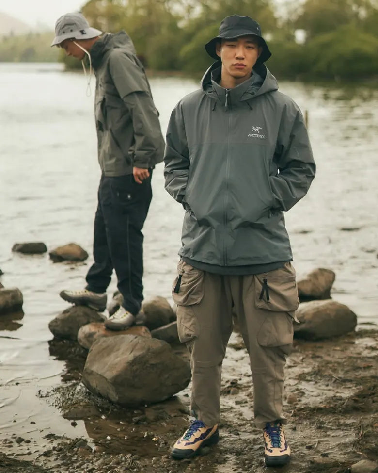 Two models wear Arc'teryx jackets at a river