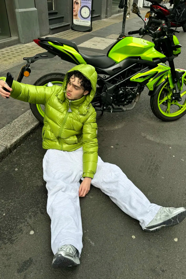 Streetwear look with a green puffer jacket and joggers on a man, from an END. editorial about styling the New Balance M1906R sneaker.