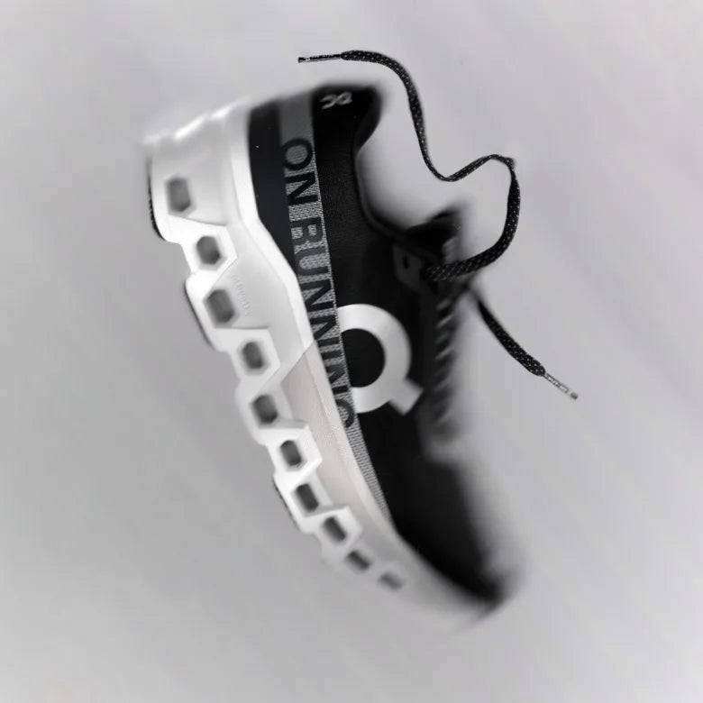 On Cloudmonster running shoe suspended in mid‑air with a motion‑blur effect.