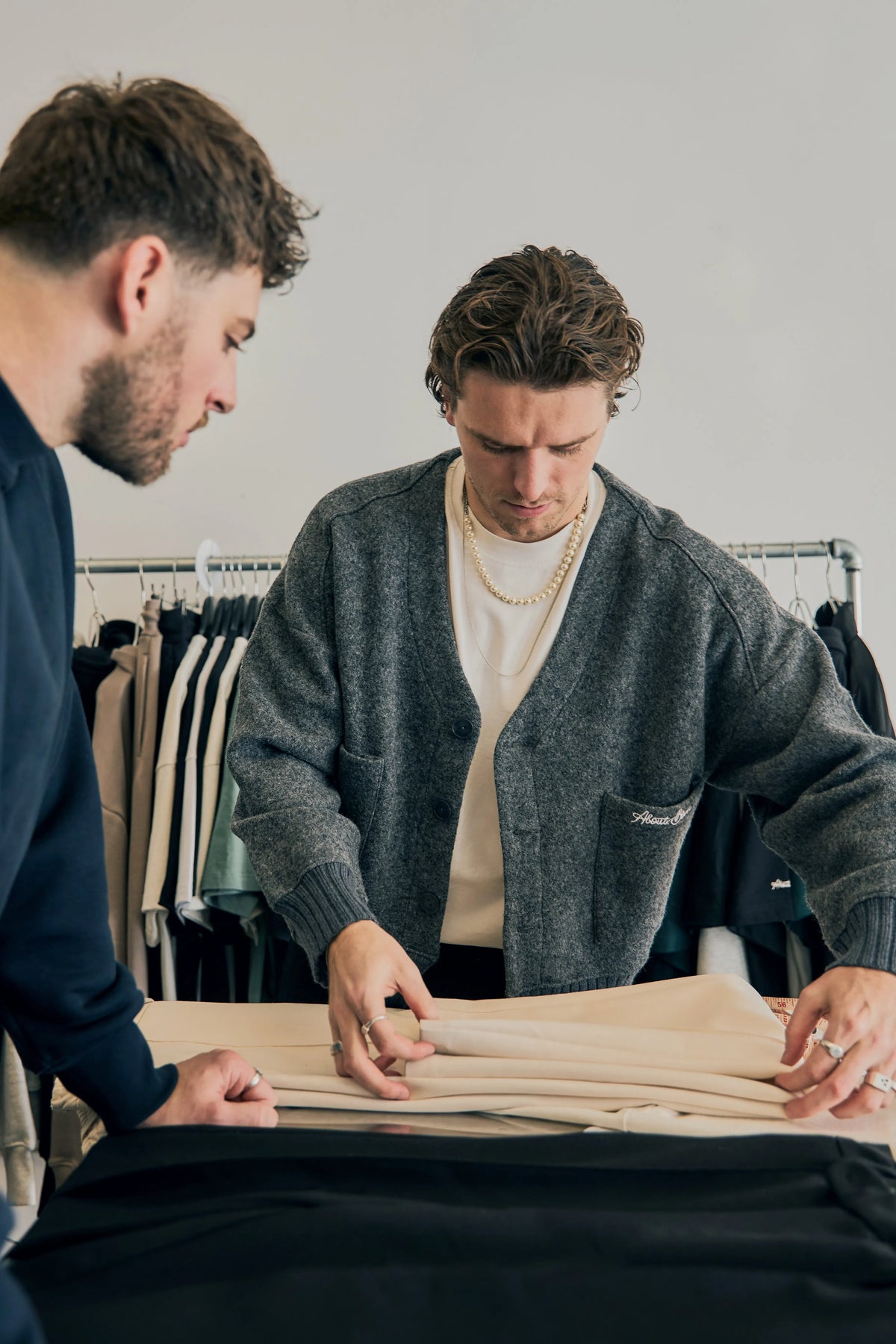 Two men folding and examining a pair of trousers in a design studio.