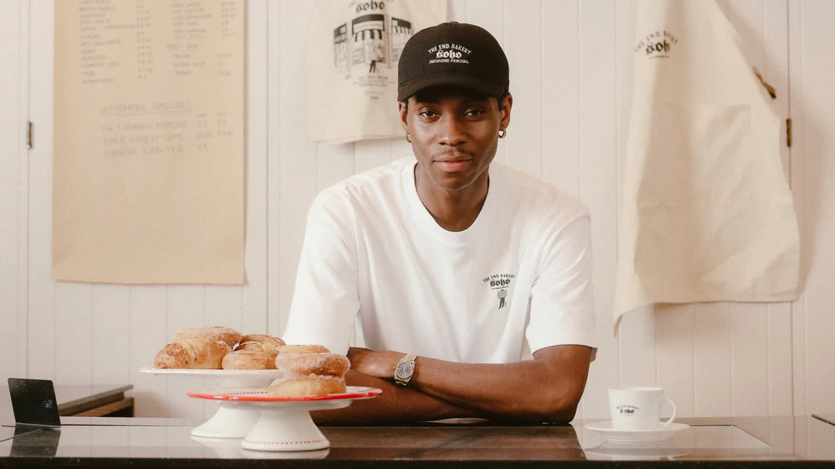 Man in bakery wearing a Percival hat and tee