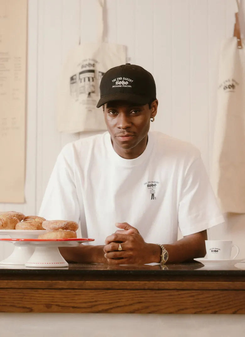 Man in bakery wearing a Percival hat and tee