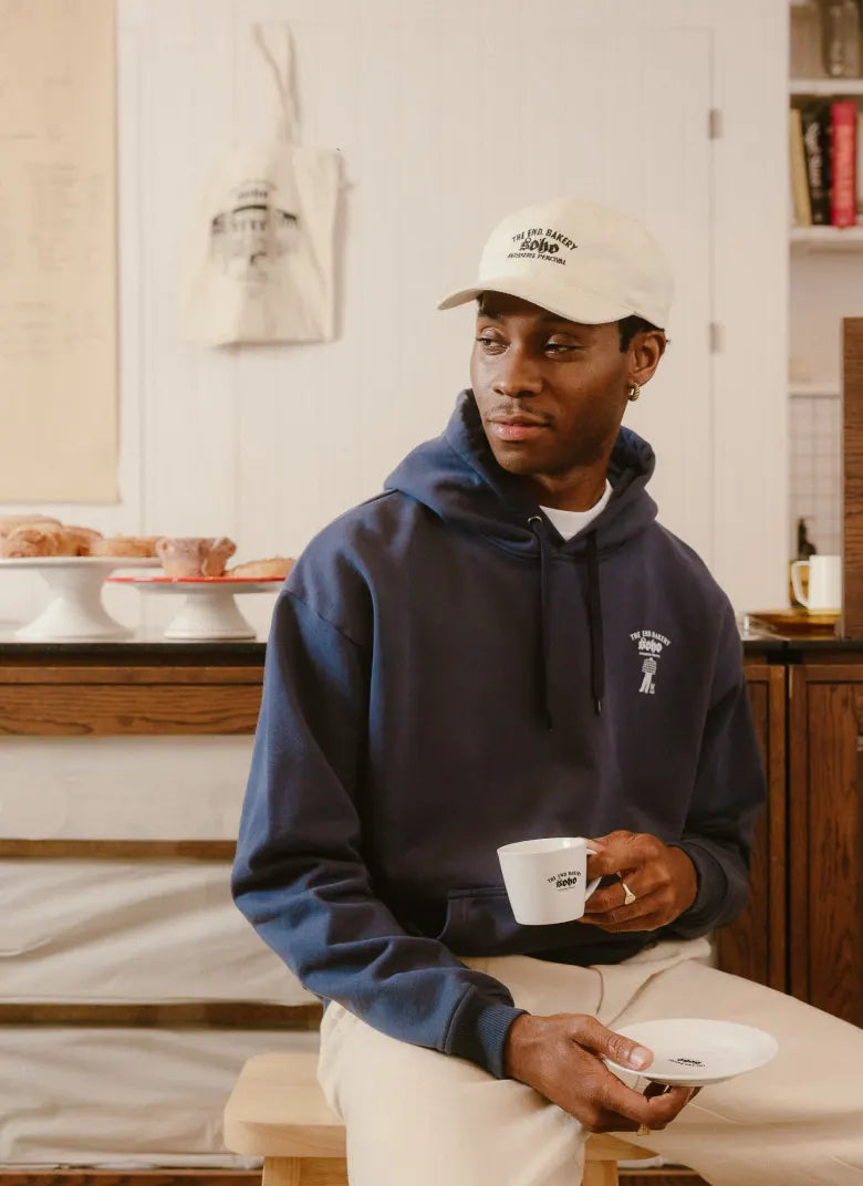 Man in bakery wearing a Percival hat and hoodie
