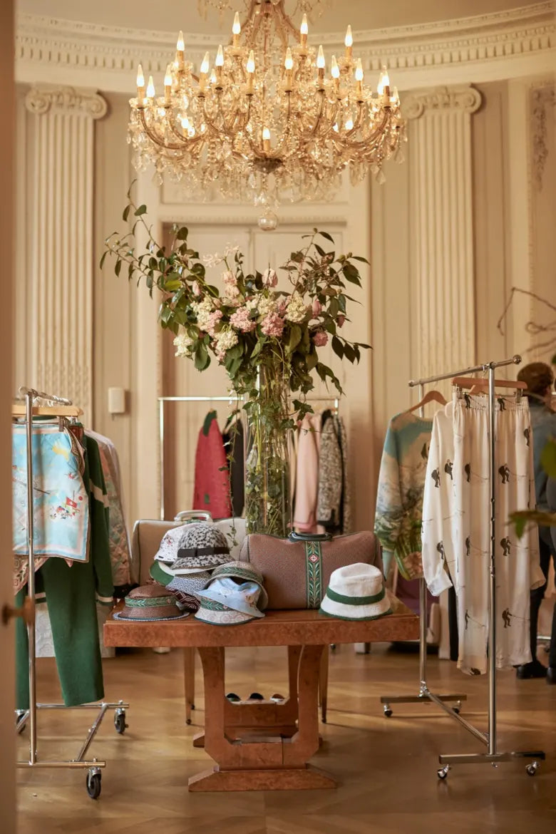 Casablanca clothing hanging on rails in a luxurious room with a chandelier. 