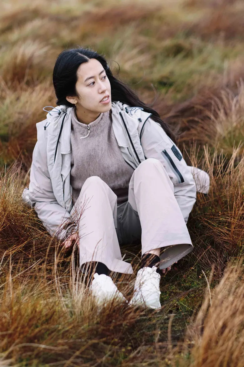 A woman sat on the moors wearing the END. x ON Cloudhorizon sneakers.