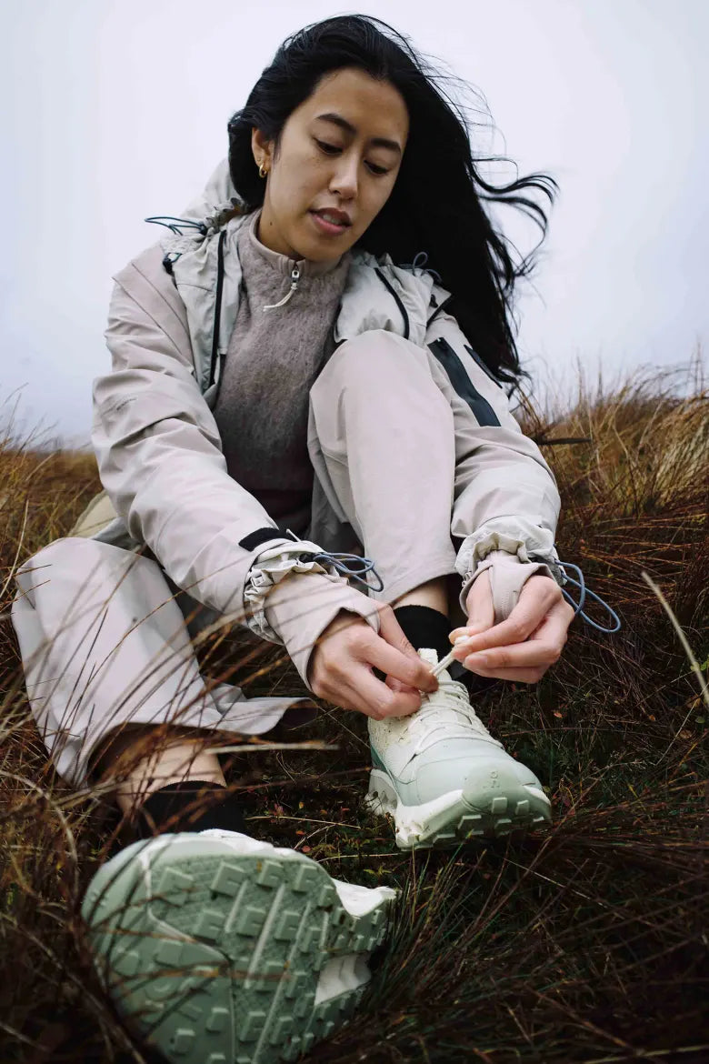 A woman lacing up the END. x ON Cloudhorizon sneakers.
