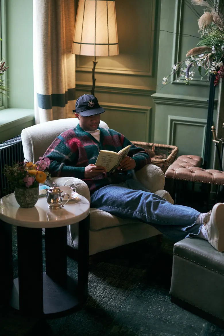 Man reading and wearing Pop Trading Company and Gleneagles collaboration clothing