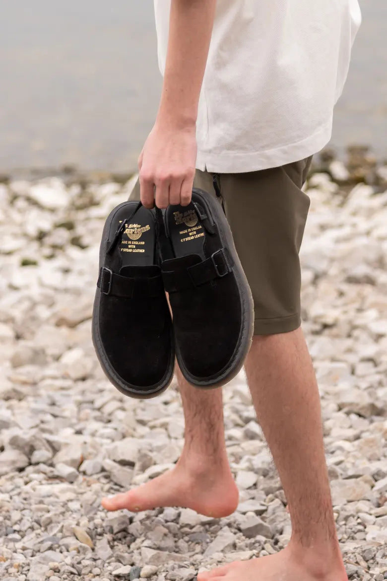 Man walking on beach with Dr. Martens’ Jorge Mule in hand