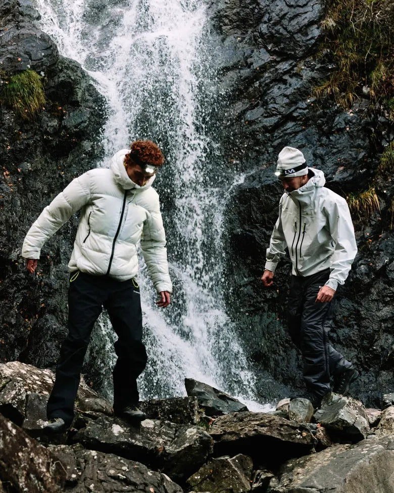 Two people wearing END. x Montane outerwear in front of a waterfall.