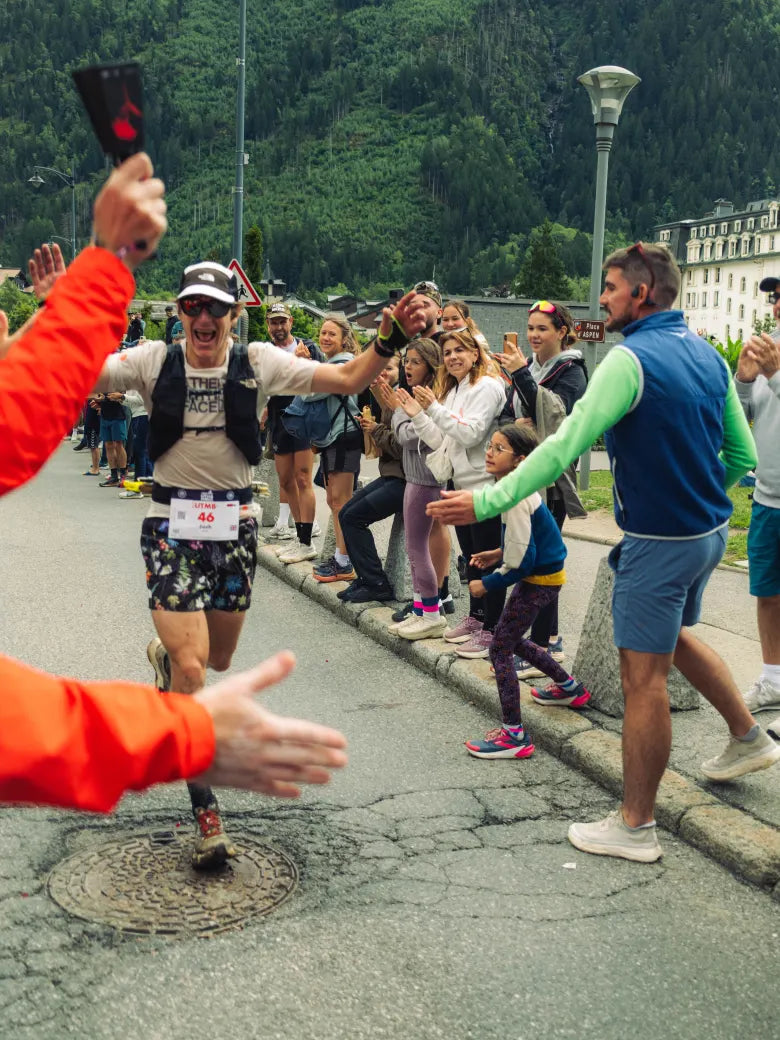 A man running the Chamonix ultra wearing The North Face and high-fiving spectators.